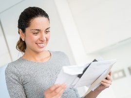 A woman pulling out her ballot papers from an envelope. 